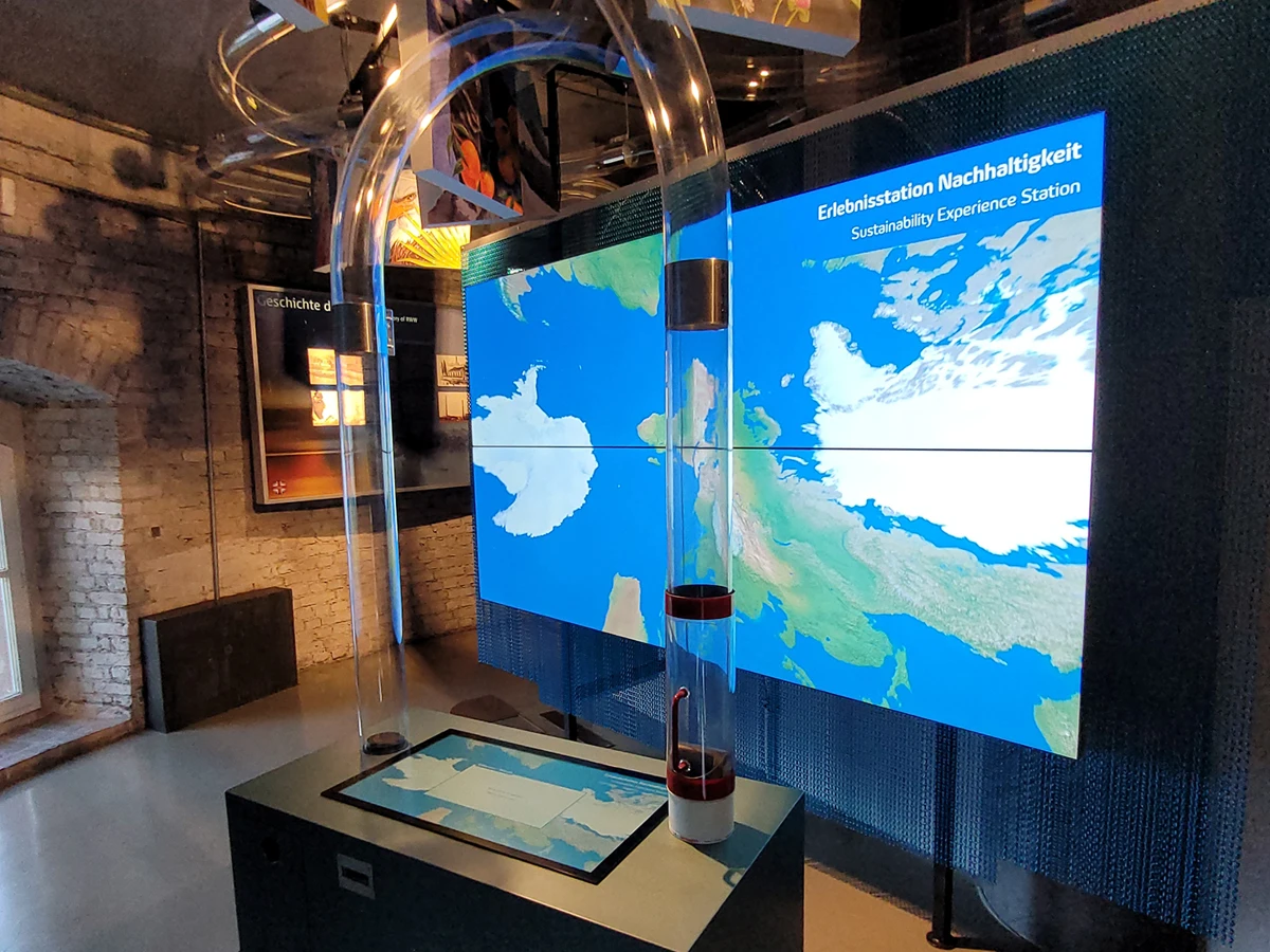 Erlebnisstation Nachhaltigkeit mit transparenter Rohrpost, interaktivem Tisch und großer Weltkarte im RWW Aquarius Wassermuseum.